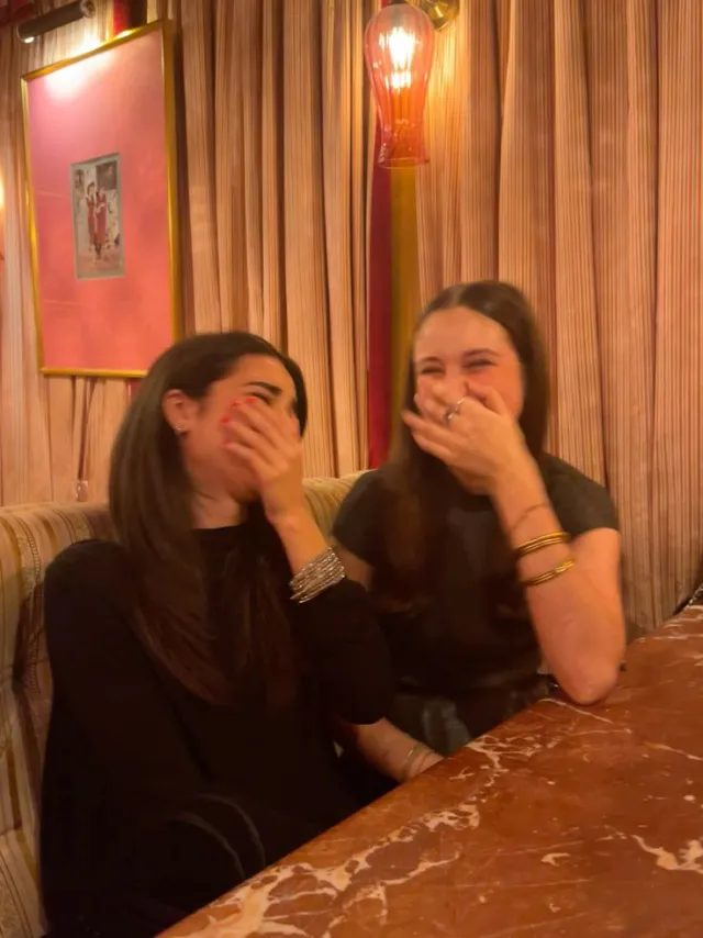 Two friends laughing together at a table
